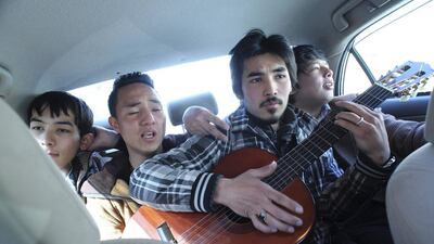 Members of an Afghan band Tanin, Mahmoud Hejran (2nd left) and Zabih Hosseini (centre) play the guitar and sing as they travel back to their music studio after performing on a live TV programme.