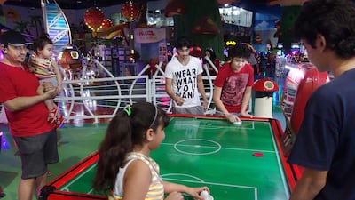 Sultan Nawaf holds daughter Mira while watching his other children play ice hockey at Wanasa Land in Al Wahda mall. Delores Johnson / The National