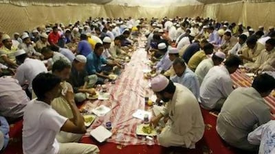 Labour workers break the fast in a tent by the Red Crescent during the first day of Ramadan in Mussafah.