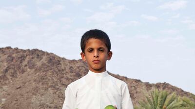 Mohammad Khalifa poses for the camera with some locally grown mangoes on a traditional Emirate farm in Wadi Al Tuwa.