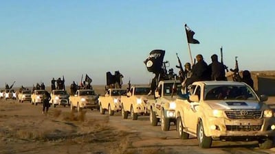 ISIS militants hold up their weapons and wave flags on their vehicles in a convoy on a road in Raqqa, Syria, in 2018. AP