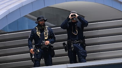 Los Angeles Airport Police officers look through binoculars as they stand on a rooftop to provide security before the arrival of Iran's national football team at Los Angeles International Airport on June 14, 2026. AFP