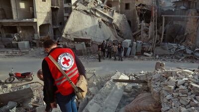 An International Red Cross worker stands above the rubble of a destroyed building in Douma in the Syrian rebel enclave of Eastern Ghouta on March 5, 2018. AFP