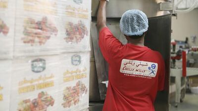 A worker loads a machine with empty plastic bottles to be filled with white vinegar at the Chilly Willy manufacturing facility in Dubai, June 3, 2015.