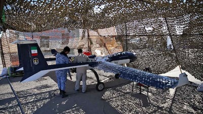 Technicians inspect a military vehicle in a camouflage enclosure. AFP