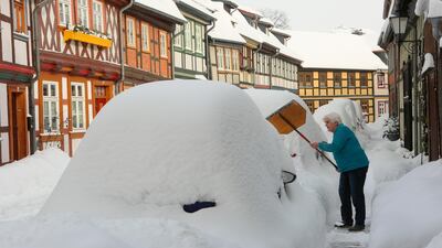 A woman clears the pavement of snow outside her front door in Wernigerode, Germany. AP