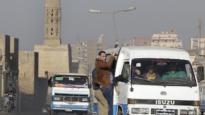Egyptians hang out of a microbus in front of the ancient gates of the historical Fatimid Cairo. Amr Nabil/AP Photo