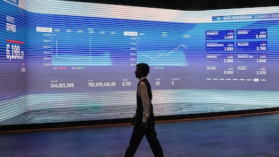 A man walks past a screen displaying stock indices at the Dubai Financial Market, which fell sharply at open on March 4 after two days of suspension. AFP