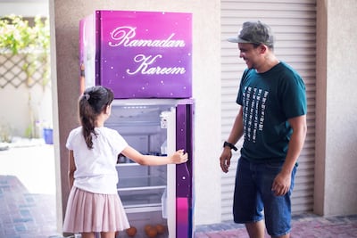 Young volunteer Lara Kunsleben with street artist Sainz, who has given the fridge outside her home a bright new look in keeping with the Ramadan spirit. Reem Mohammed/The National