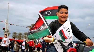 A boy rides a bicycle decorated with flags through Tripoli as the country celebrates the 10th anniversary of the uprising. AFP