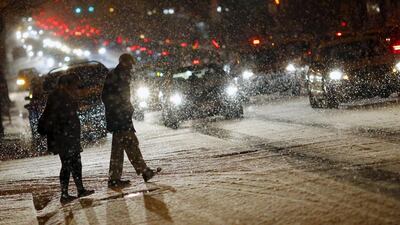 People cross a street as it snows in Washington DC on January 20, 2016. Icy roads and freezing temperatures prompted school closings and emergency preparations in several states as snow began to fall ahead of a major storm expected to blast snow across the northeast this weekend. Carlos Barria / Reuters