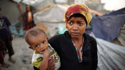 A woman from the Akhdam community carries her son.