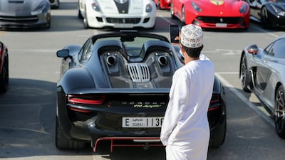 An onlooker takes a photo of a Porsche 918 Spyder, foreground, in front of several Ferraris and a Chevrolet Corvette. Chris Whiteoak / The National