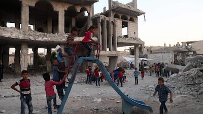 Syrian children, who fled their homes in Ghouta's al-Marj town, play amidst the debris of buildings in the town of al-Nashabiyah in the eastern Ghouta region, a rebel stronghold east of the capital Damascus on June 27, 2017. / AFP PHOTO / AMER ALMOHIBANY