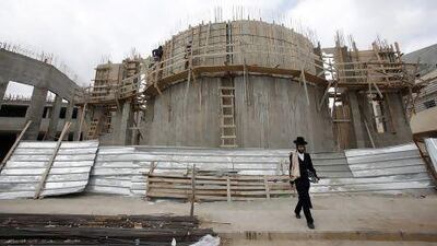 Palestinian labourers construct a synagogue as an ultra-Orthodox Jewish man walks past in the West Bank Jewish settlement of Beitar Ilit, near Bethlehem.