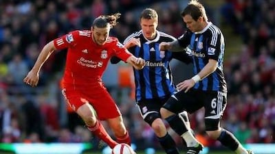 Liverpool's Andy Carroll, left, fends off Stoke duo Glenn Whelan and Robert Huth. Alex Livesey / Getty Images