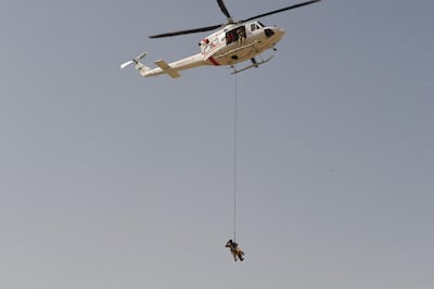 A policeman is suspended from a helicopter, with a K9 dog in tow. Courtesy Dubai Police