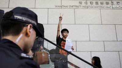Student leader Joshua Wong flashes a victory sign as he arrives at the police headquarters in Hong Kong. Vincent Yu / AP Photo