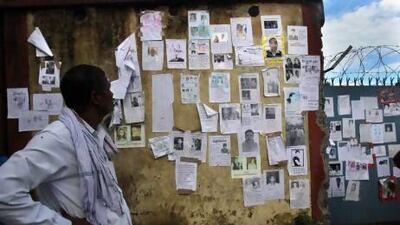 An Indian man looks at a wall covered in special announcements and pictures of missing people near the airport gate in Jollygrant, in northern Indian state of Uttarakhand.