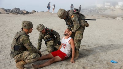 Spanish soldiers help an injured migrant on a beach. Reuters