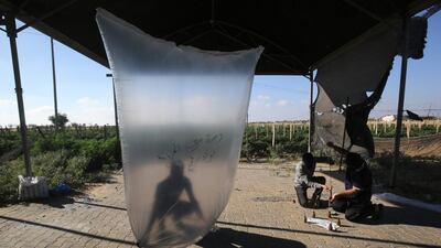 Palestinians inflate plastic bags before being attached with incendiary devices and flown towards Israel, near Rafah along the border between the Gaza Strip and Israel. AFP