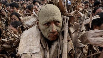 Catholic worshippers covered in mud and dried leaves gather outside a church during the Taong Putik Festival in the Philippines. EPA