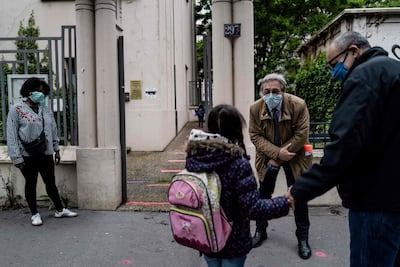 The school director welcomes every pupils as they arrive at school on its reopening day, on May 14, 2020 at a school in Lyon, as primary schools in France re-open this week and the country eases lockdown measures taken to curb the spread of the Covid-19. AFP
