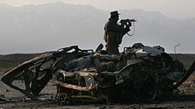 A policeman maintains a vigil near the remains of a car used by a suicide bomber in Bagram.