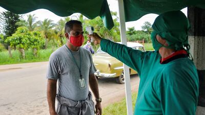 A medical worker checks the body temperture of a man in San Jose de las Lajas, Mayabeque province, Cuba. AFP