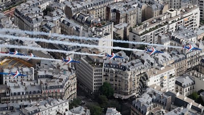 A view taken from a helicopter shows Alphajet aircrafts from the French elite acrobatic flying team Patrouille de France (PAF) releasing smoke in the colours of the French national flag as they fly above the rooftops of Paris during the annual Bastille Day military parade on the Champs Elysees. Thomas Samson / AFP