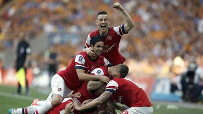 Arsenal players celebrate with Welsh midfielder Aaron Ramsey (ground-obscured) after he scores the third and winning goal during the FA Cup final against Hull City on Saturday. Adrian Dennis / AFP / May 17, 2014