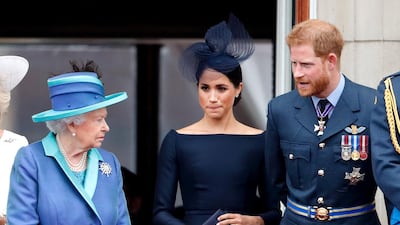 Queen Elizabeth speaks with Meghan Markle and Prince Harry during a flypast to mark the centenary of the Royal Air Force from the balcony of Buckingham Palace in July 2018. Getty Images