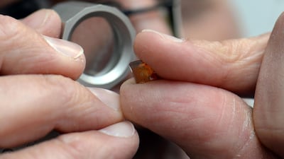 A synthetic diamond is checked with a magnifying glass. Lab-grown gems are challenging the value of natural diamonds. Harald Tittel/ AP