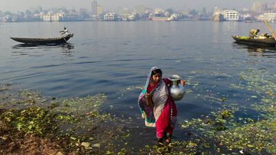 A Bangladeshi woman collects water from the polluted Buriganga river in Dhaka. Twenty million Bangladeshi people are still drinking water contaminated with arsenic, two decades after the toxin was discovered in the supply, says Human Rights Watch. Munir Uz Zaman / AFP