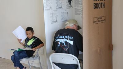 An early voter (right) casts his ballot as another's child waits doing homework, during early voting at a polling station in Huntington Beach, California. EPA