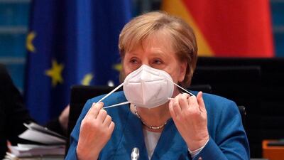 German Chancellor Angela Merkel takes off her face mask as she prepares to lead the weekly cabinet meeting at the Chancellery in Berlin. AFP