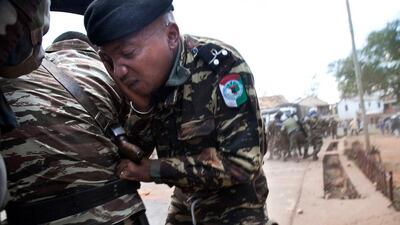 A police officer takes covers as protesters throw stones during a demonstration in Soamahamanina, China, on September 29, 2016, against the presence of the Chinese mining company Jiuxing, which they accuse of forcing the rental of land, and destruction of property and the environment. Rijasolo / Agence France-Presse