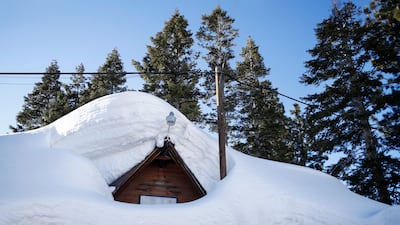 A roof of a house barely poking out underneath piles of pillowy snow. EPA