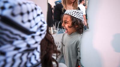 A boy checks out his new Palestinian headscarf in a mirror shaped like Palestine