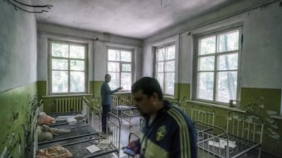 Tourists walk around rusty child-sized bed frames in a former preschool building. Bloomberg