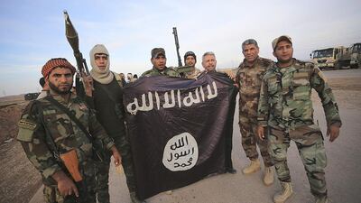 Iraqi Shiite fighters pose with an ISIL flag they pulled down on the front line in Jalawla in Diyala province on Sunday. Iraqi forces said they had retaken two towns north of Baghdad from the Islamists. Reuters