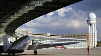 A vintage American DC3 on the tarmac under the giant semi-circular canopy of Tempelhof airport.