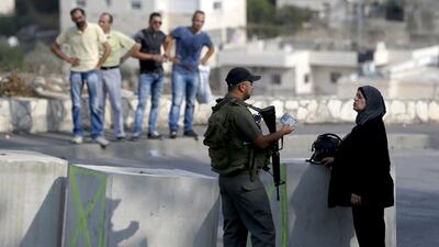 An Israeli border guard checks the ID of a Palestinian woman at a newly erected checkpoint in East Jerusalem on October 19, 2015. Ahmad Gharabli AFP