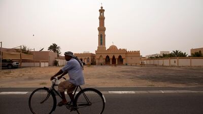 A man rides a bicycle past a mosque in Madinat Zayed, Abu Dhabi. Christopher Pike / The National