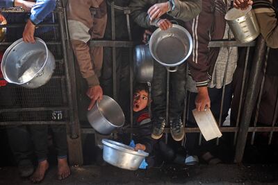 Palestinians gather to receive food being distributed along the roadside at the Nuseirat refugee camp in the central Gaza Strip on January 11. AFP