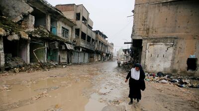 A woman walks next to damaged shops in Mosul. Reuters