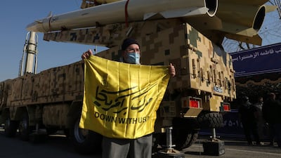 A man holds an anti-US banner in front of missiles displayed in an exhibition in Tehran, Iran. AP
