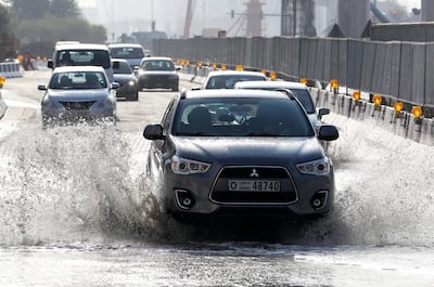 Cars drive through flooded streets in the Discovery Gardens area of Dubai after a heavy winter deluge. Pawan Singh / The National