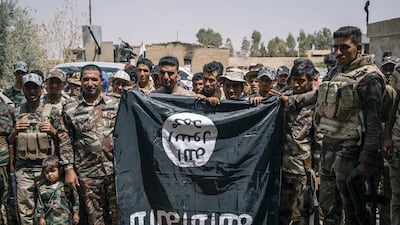 Sheikh Nozhan Selman, second from the right, poses for a picture with his men holding an Islamic State flag they captured in Hajj Ali, Iraq. Alice Martins / AP Photo