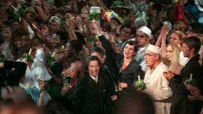Fashion designer Kenzo Takada is surrounded by models as he acknowledges the audience following his final collection for next summer at the Zenith on October 7, 1999. AFP